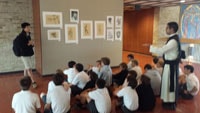 A Form VI student explains the importance of art and his favorite drawing techniques to Father Philip and the members of Form III.